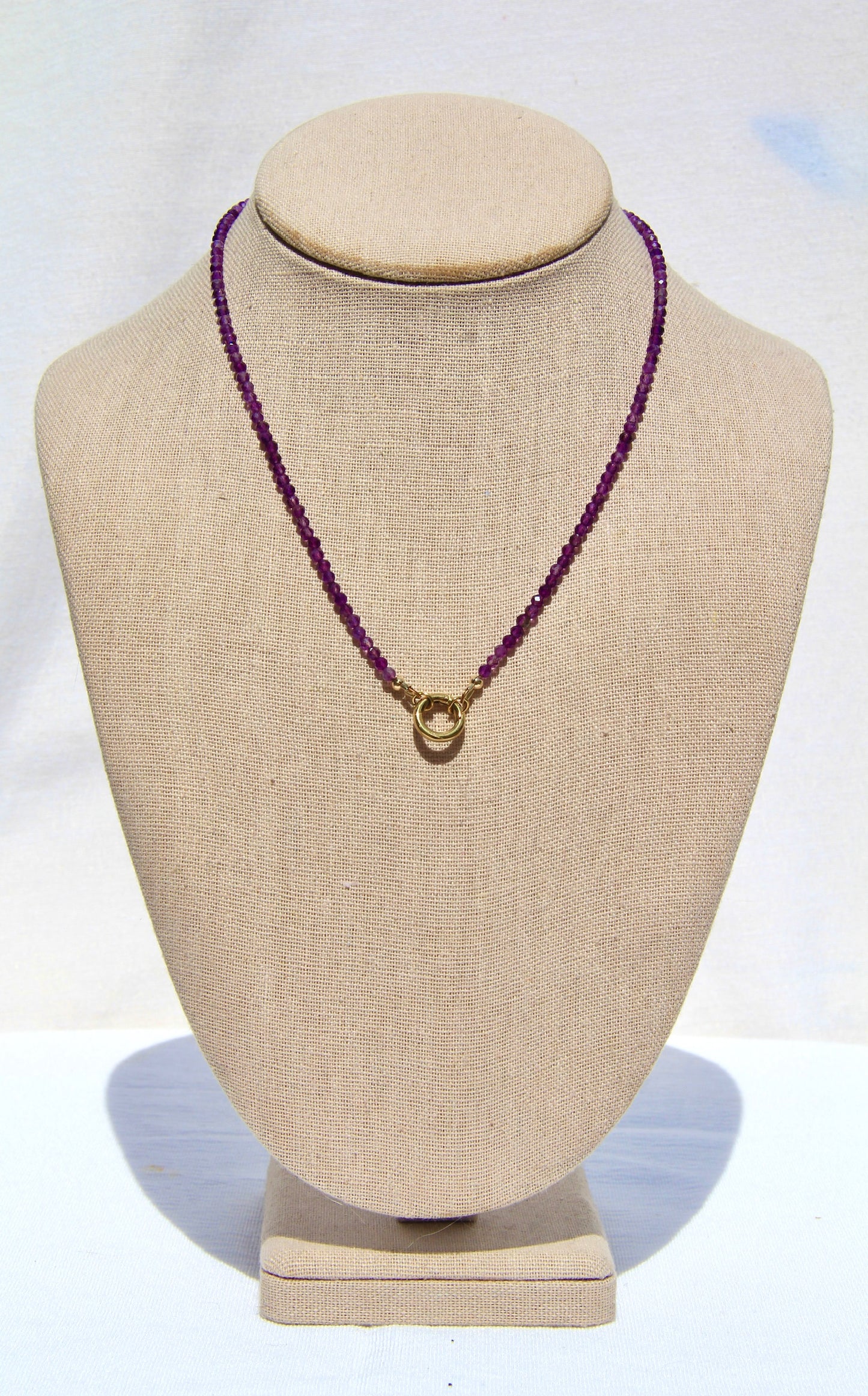 Necklace with purple beads on a beige mannequin bust against a white background