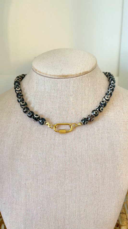 Necklace with black and white beads on a mannequin bust against a white background