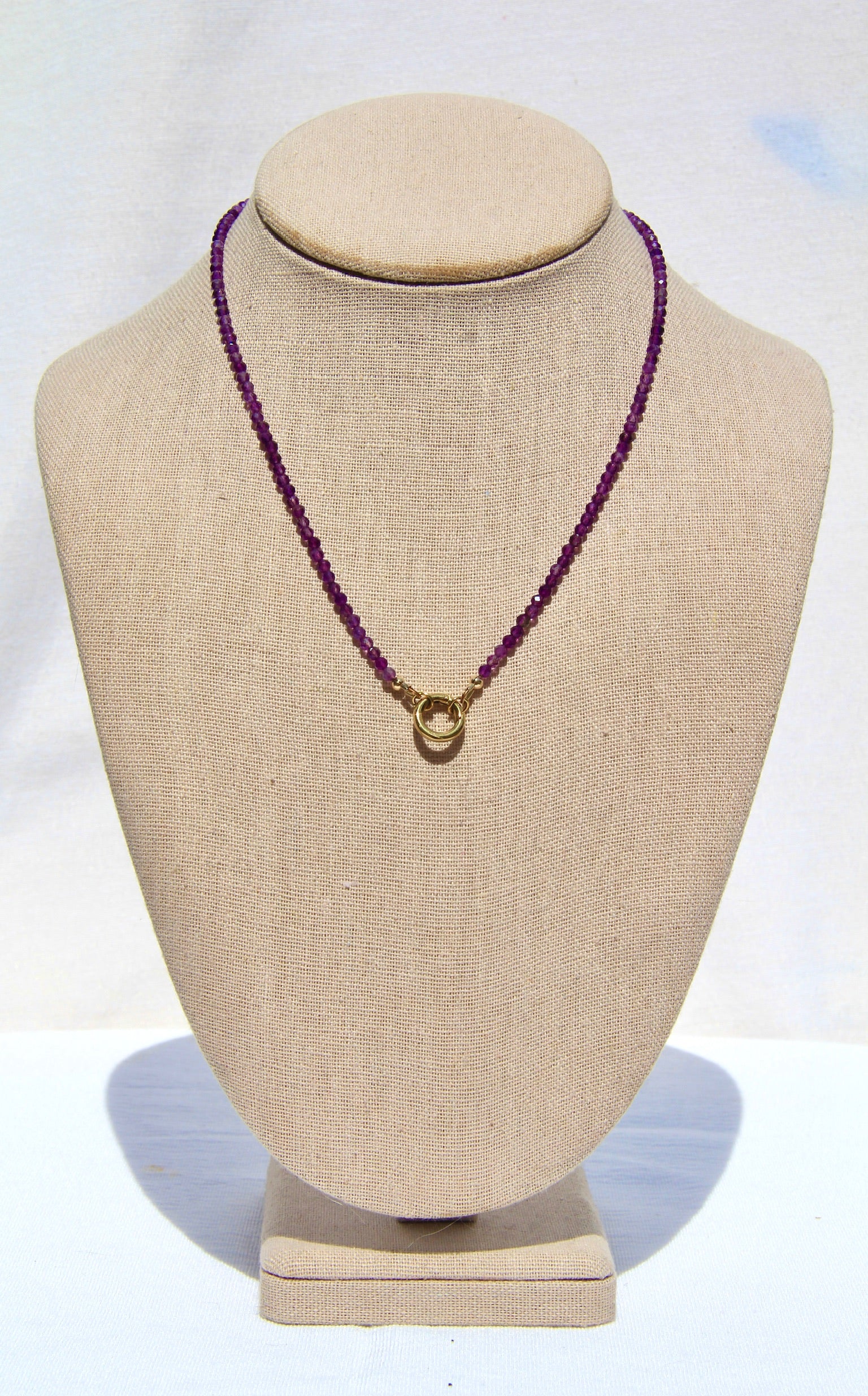 Necklace with purple beads on a beige mannequin bust against a white background