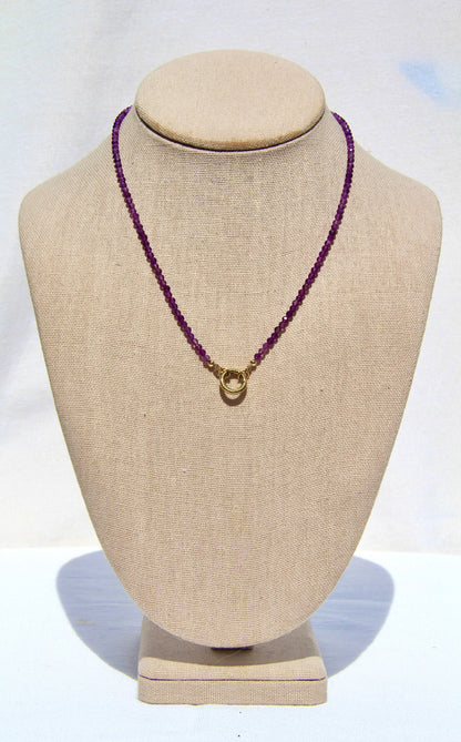 Necklace with purple beads on a beige mannequin bust against a white background
