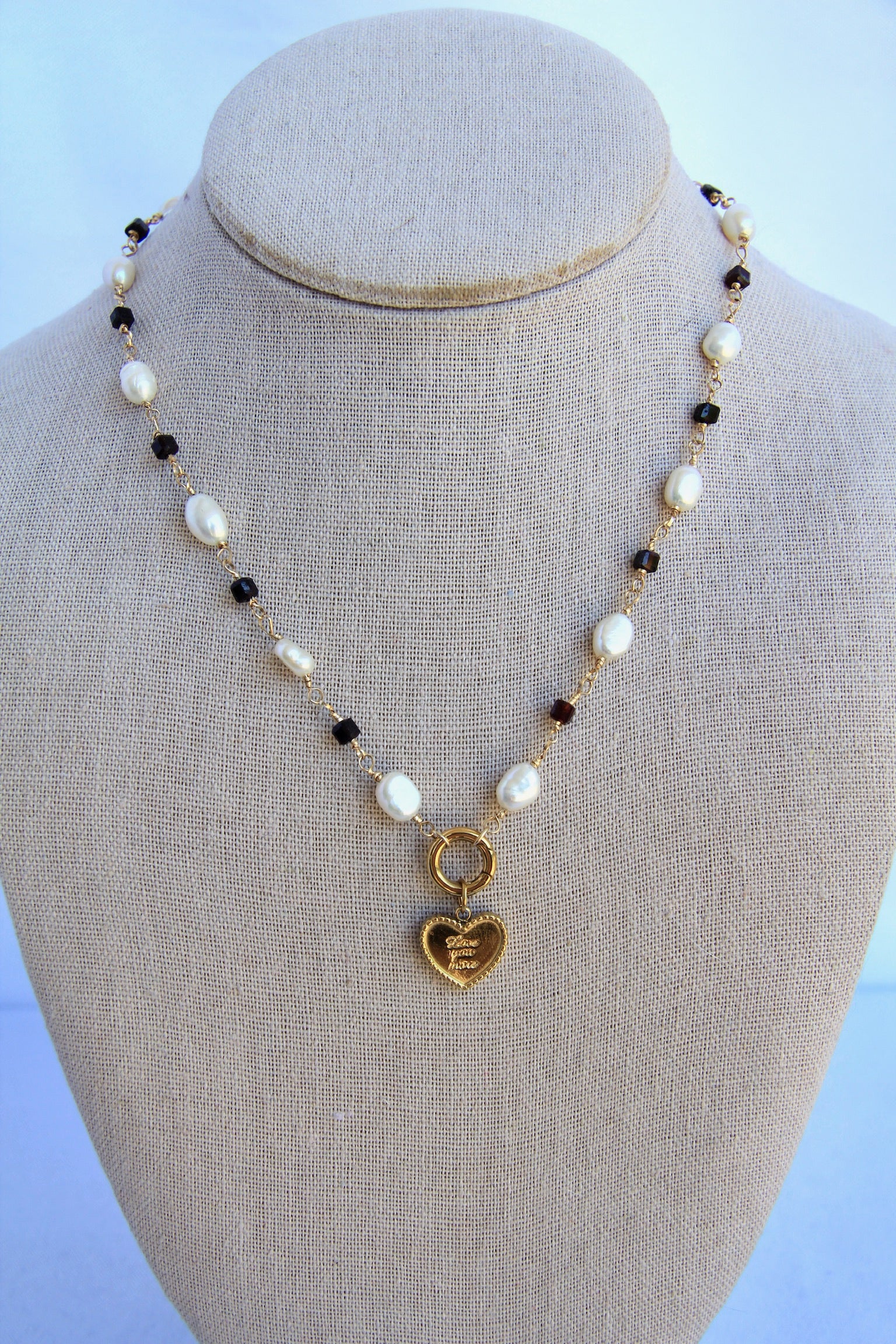 Necklace with heart-shaped pendant on a mannequin bust against a light blue background