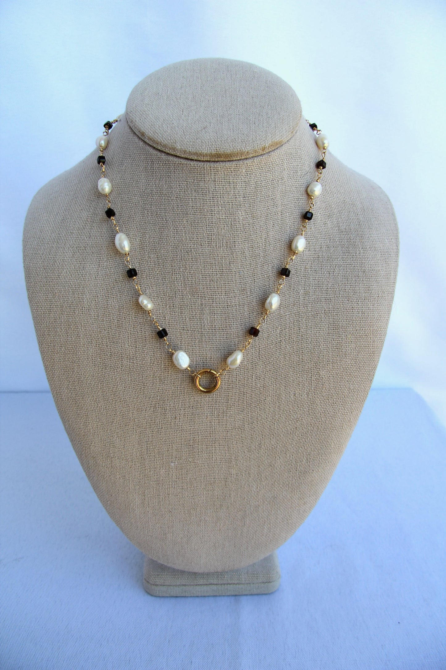 Necklace with pearls and gold accents on a mannequin bust against a white background