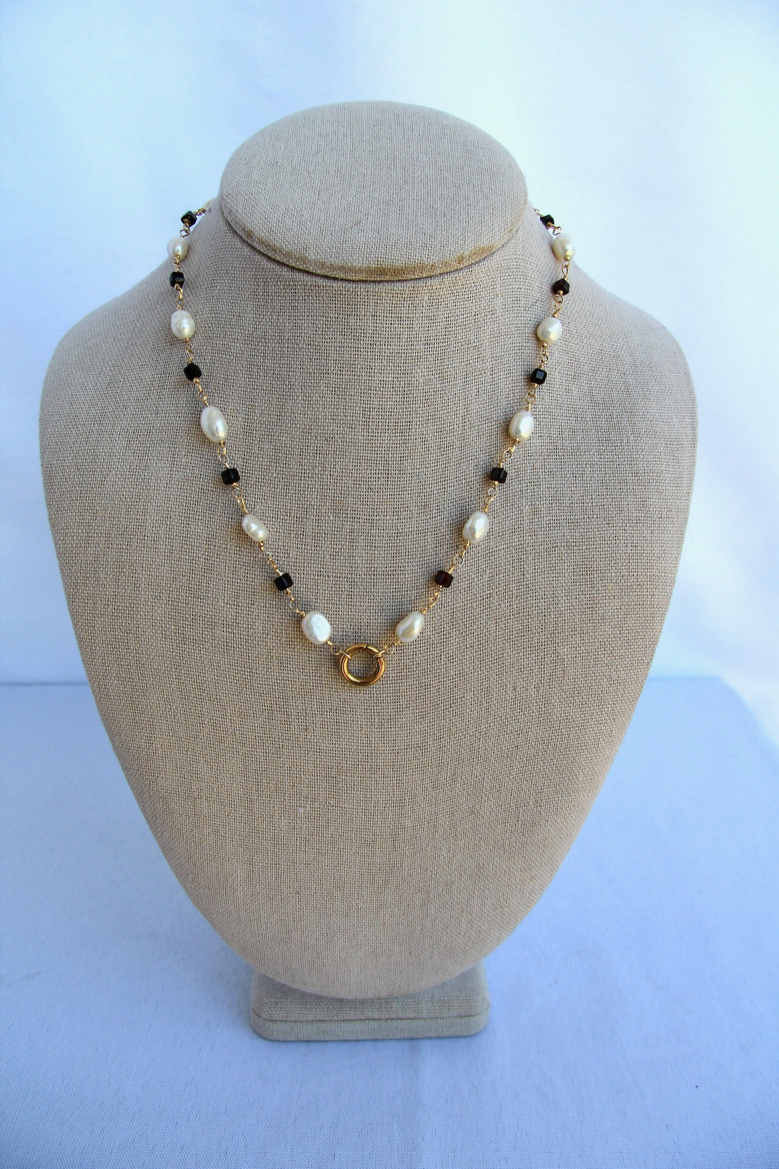 Necklace with pearls and gold accents on a mannequin bust against a white background