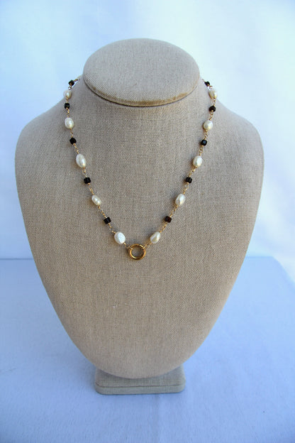 Necklace with pearls and gold accents on a mannequin bust against a white background