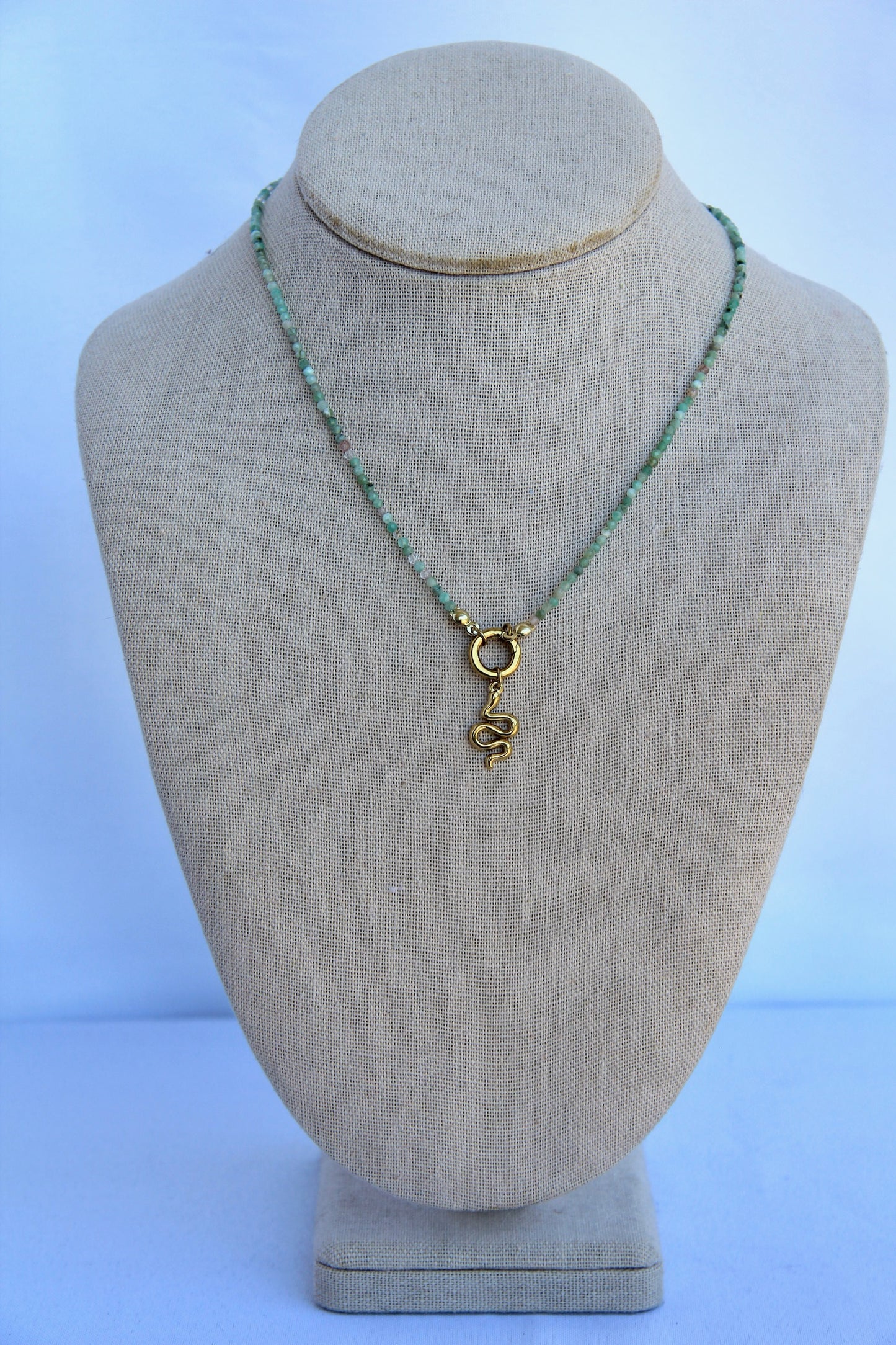 Necklace with a gold pendant on a mannequin bust against a light blue background