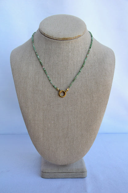 Necklace with a gold clasp on a beige mannequin bust against a white background