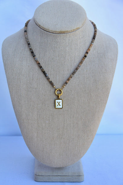 Necklace with a square pendant on a beige bust against a light blue background