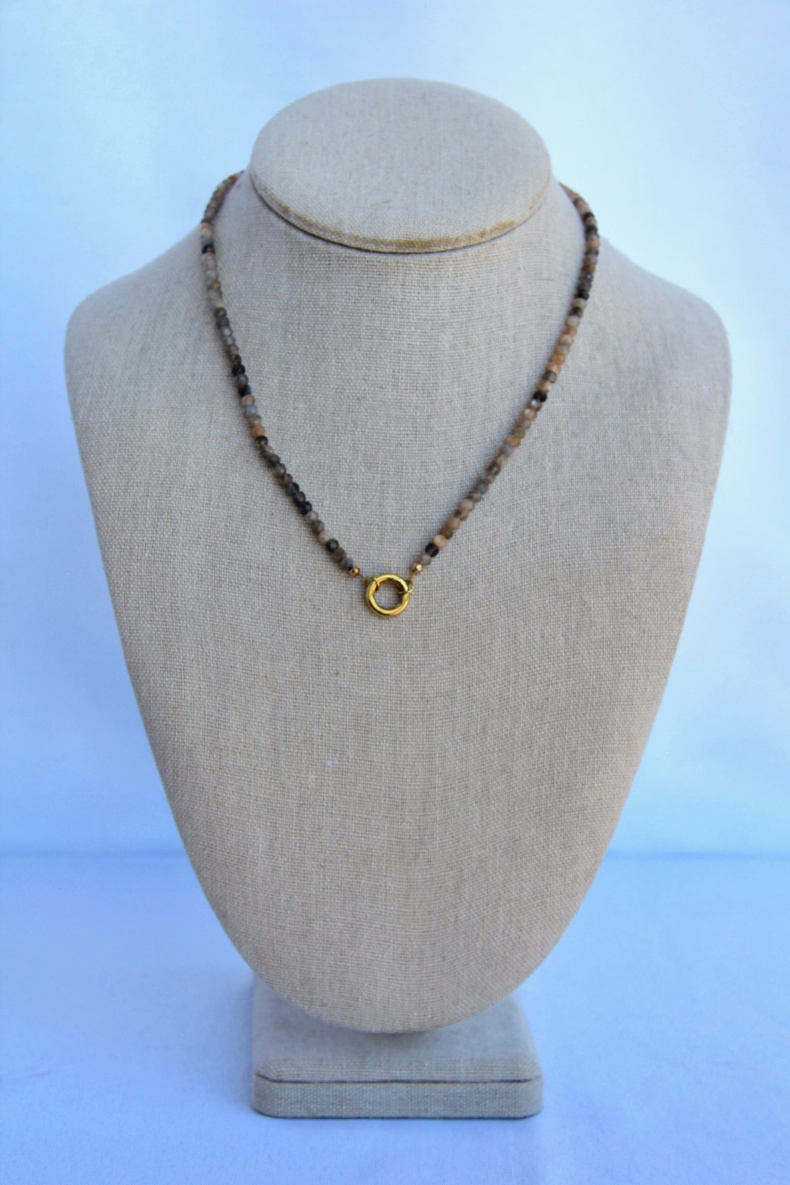 Necklace with a gold clasp on a mannequin bust against a light blue background
