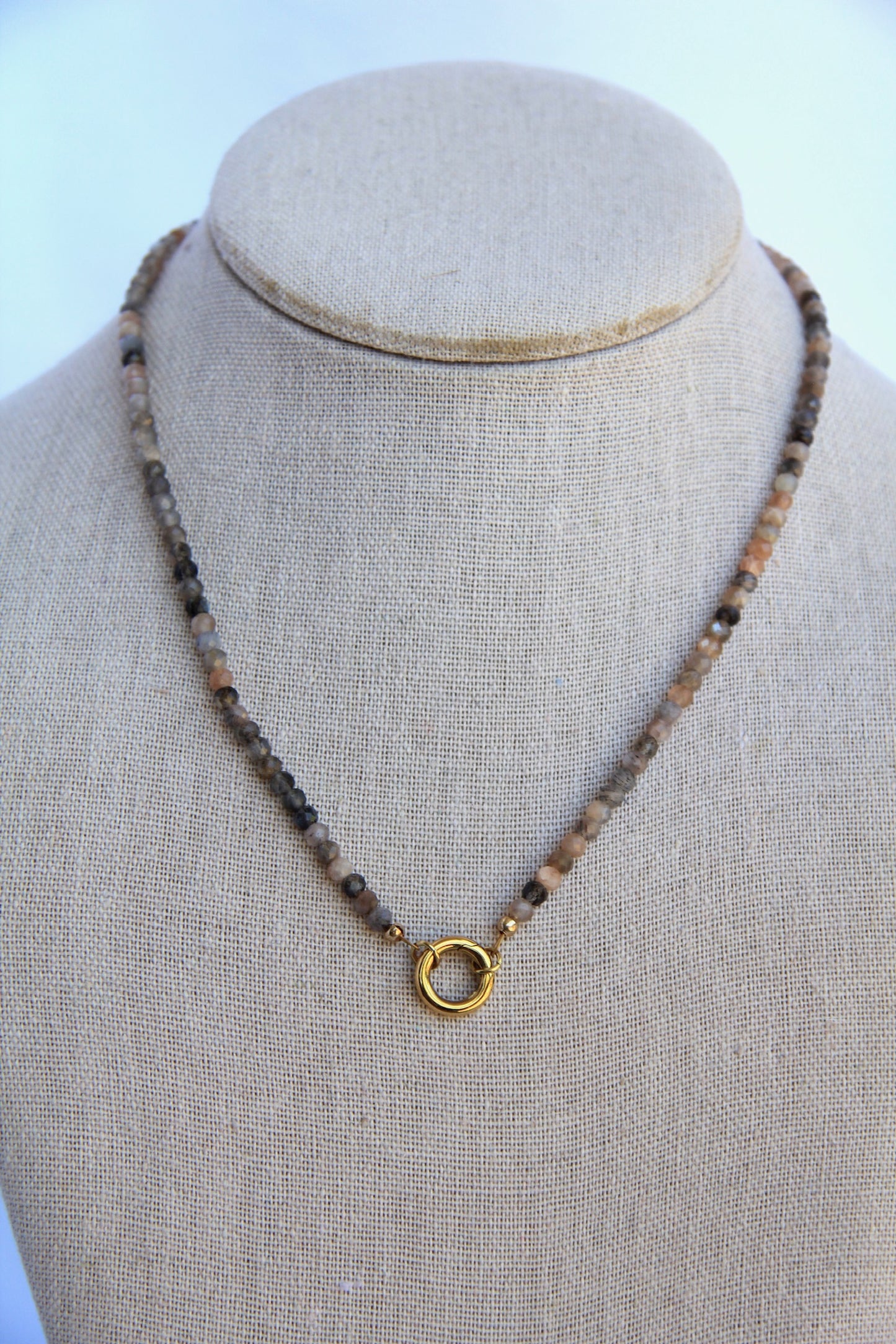Necklace with beads and a gold clasp on a mannequin bust against a light background