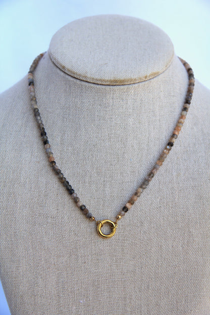 Necklace with beads and a gold clasp on a mannequin bust against a light background