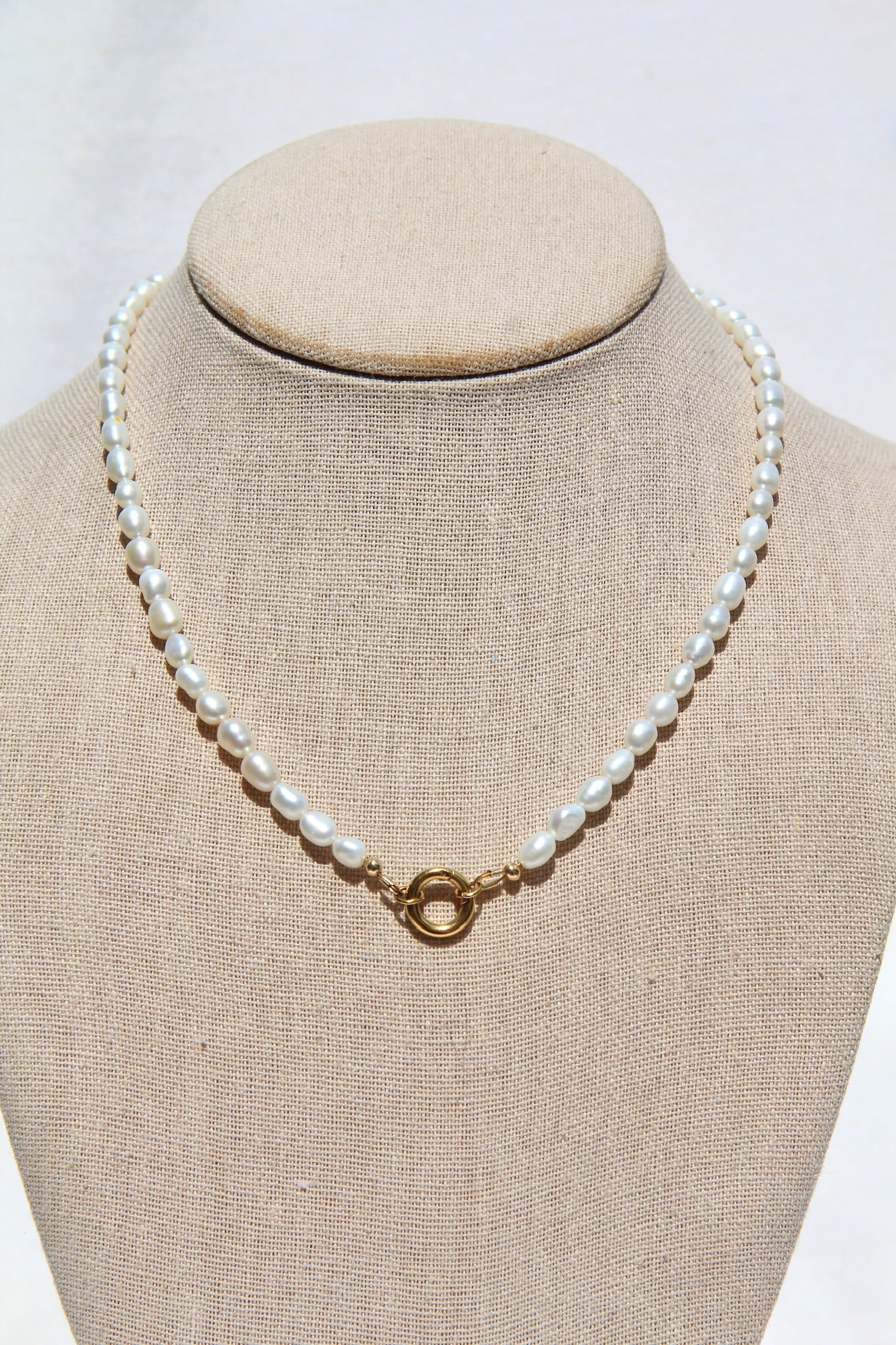 Pearl necklace on a mannequin bust with a plain background