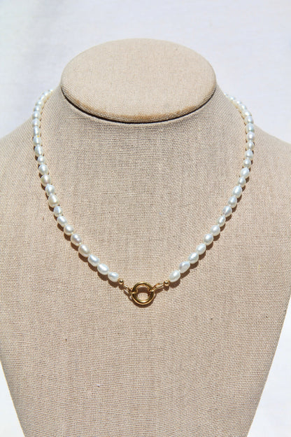 Pearl necklace on a mannequin bust with a plain background