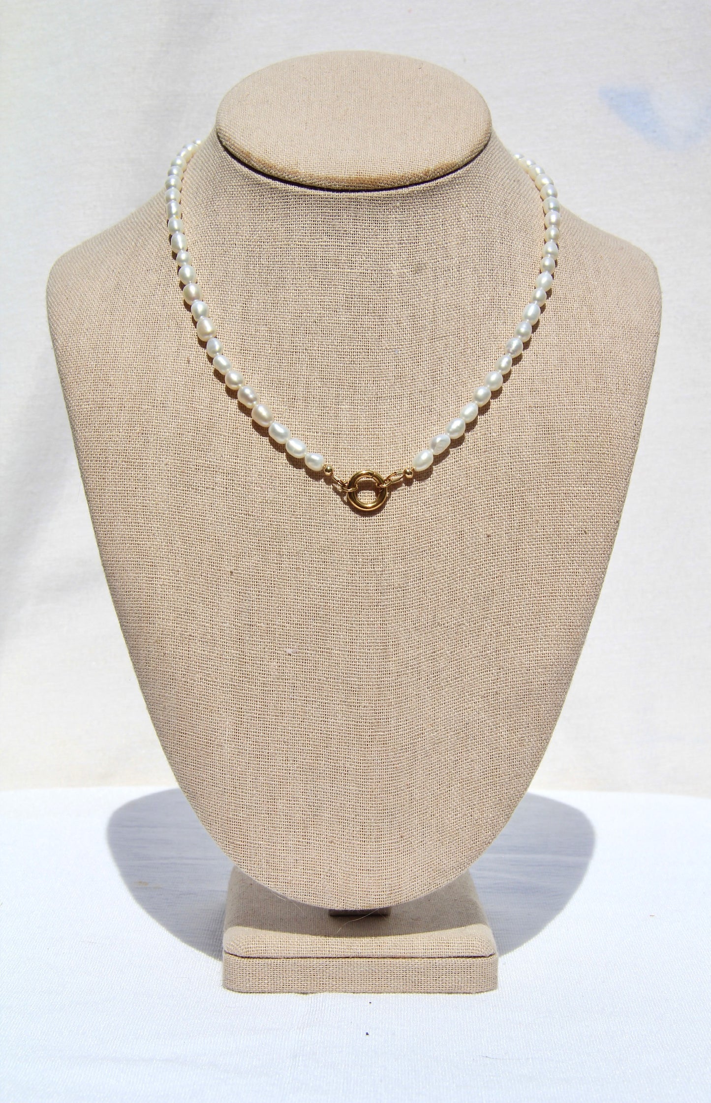 Pearl necklace on a mannequin bust with a plain background