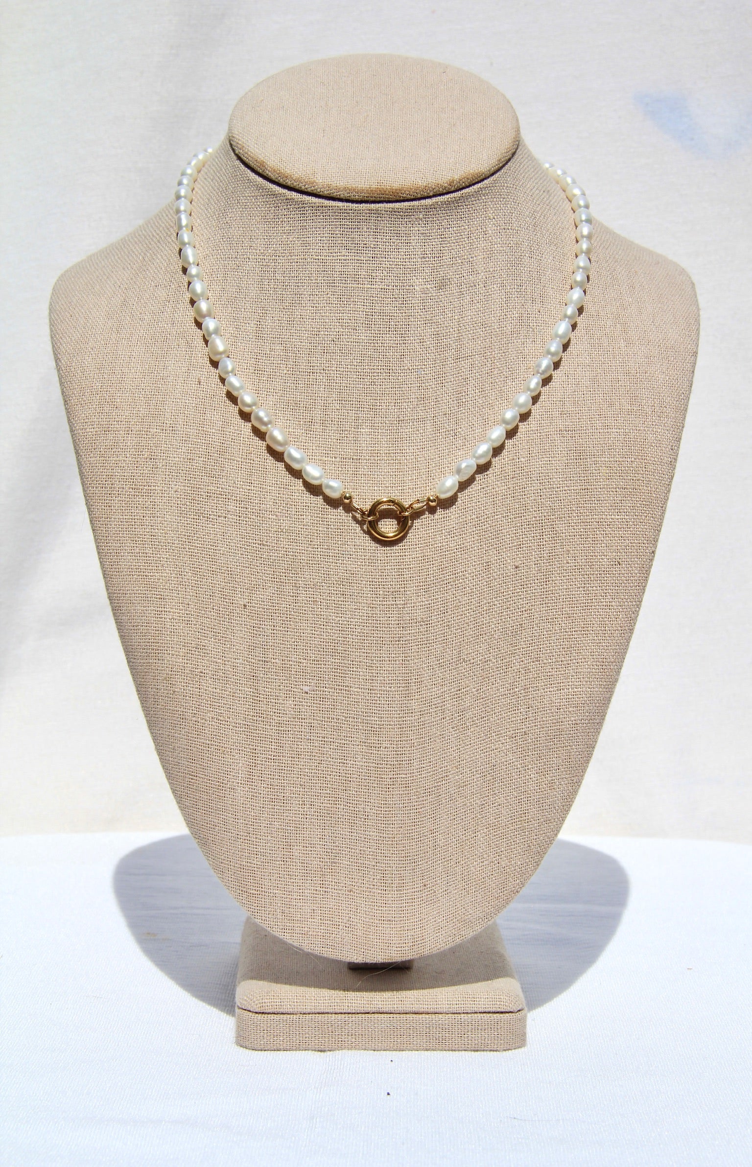 Pearl necklace on a mannequin bust with a plain background