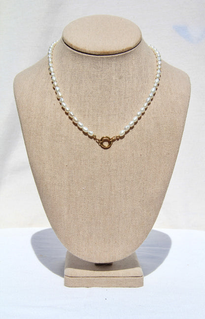 Pearl necklace on a mannequin bust with a plain background